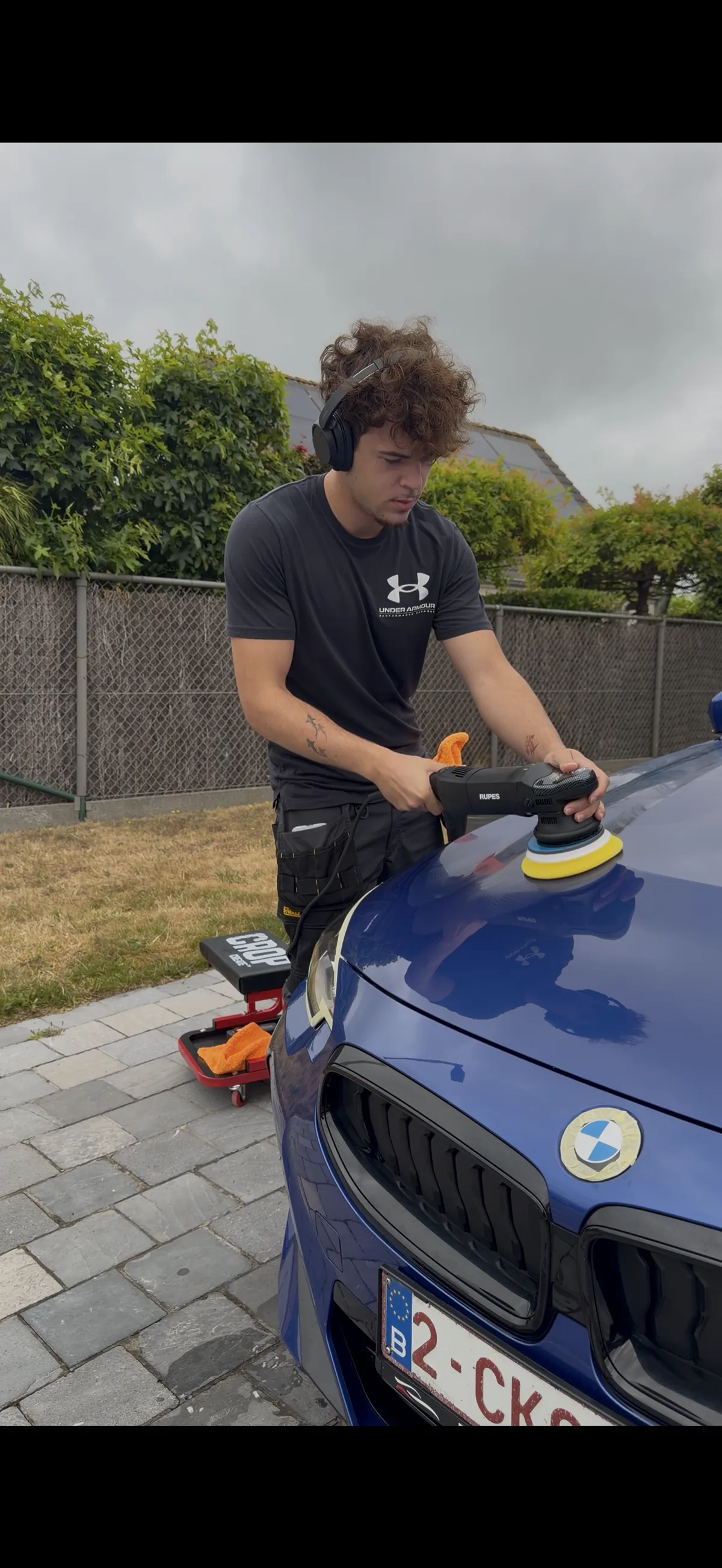 Leon van NH Detailing polijst de motorkap van een blauwe BMW